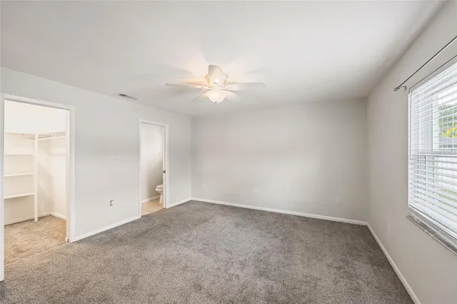 an empty room with windows and ceiling fan
