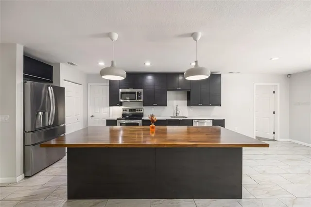 a kitchen with stainless steel appliances a refrigerator a sink a stove a microwave and island