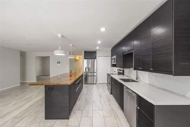 a large kitchen with stainless steel appliances a large counter top a sink a stove and a refrigerator