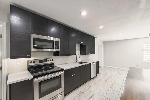 a large kitchen with stainless steel appliances a stove a sink and a microwave