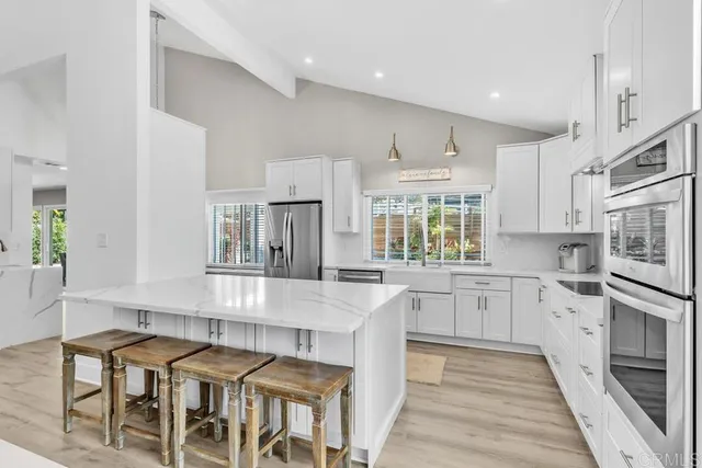 a kitchen with granite countertop white cabinets and stainless steel appliances