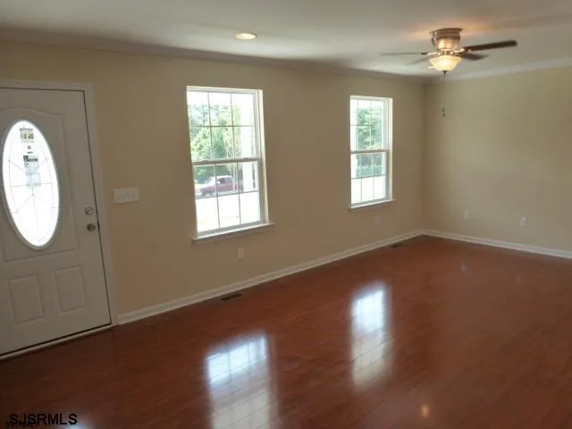 a view of an empty room with wooden floor and a window
