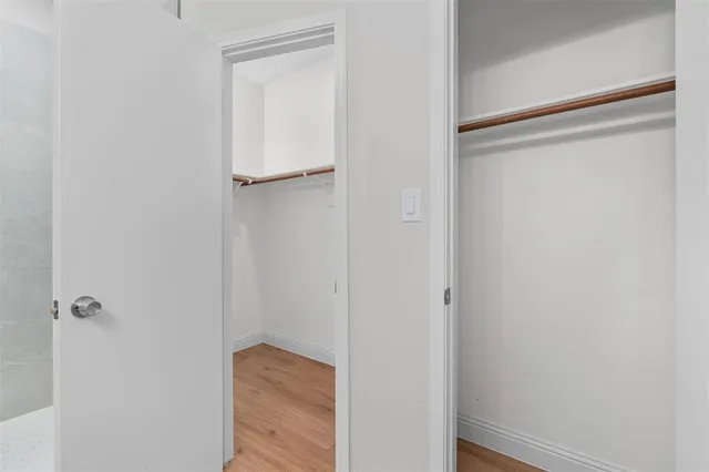 an empty room with wooden floor ceiling fan and windows