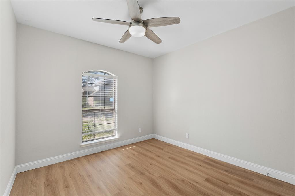 2906 Roxboro Road Euless, TX 76039 - Photo 15 of 23 an empty room with wooden floor chandelier fan and windows