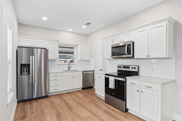 a kitchen with stainless steel appliances a stove a sink and a refrigerator