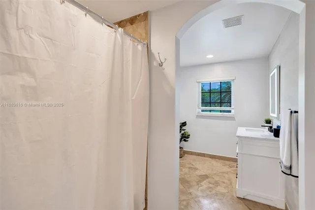 a bathroom with a sink and mirror with bathtub