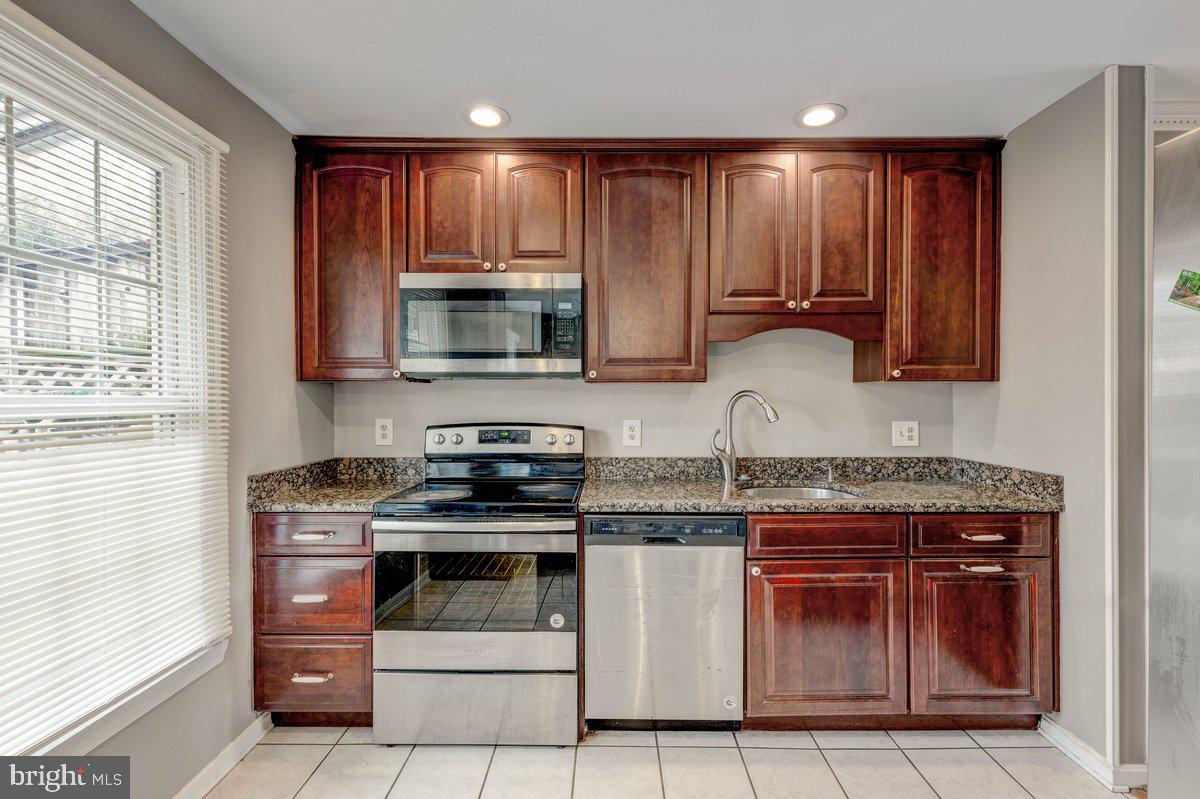 14216 Catamount Court Silver Spring, MD 20906 - Photo 4 of 30 a kitchen with granite countertop a stove top oven microwave and cabinets