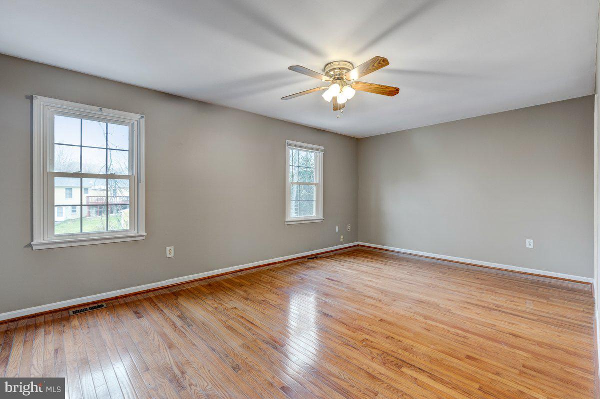 14216 Catamount Court Silver Spring, MD 20906 - Photo 6 of 30 an empty room with wooden floor chandelier fan and windows