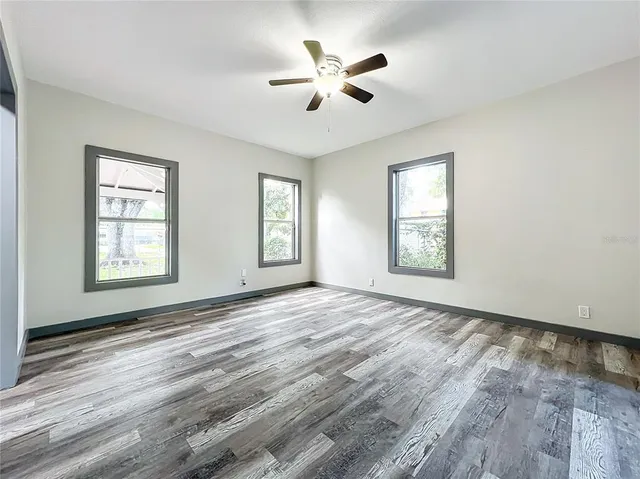 a view of an empty room with wooden floor and a window
