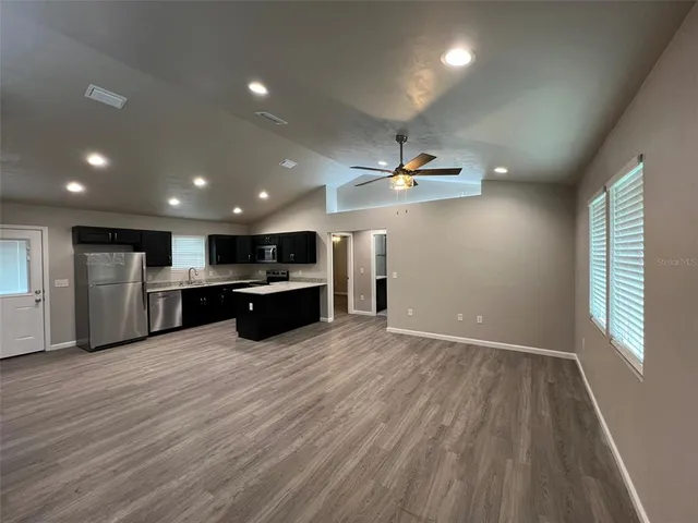 a view of kitchen with kitchen island wooden floor appliances and cabinets