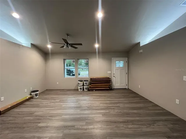 an empty room with windows and ceiling fan