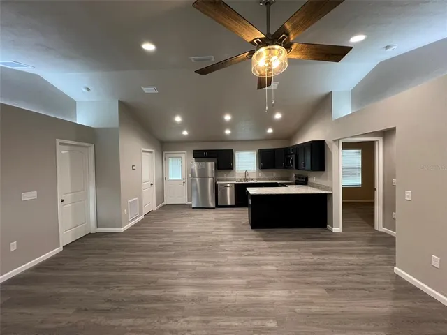 a large kitchen with kitchen island a sink stainless steel appliances and a chandelier