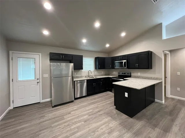 a kitchen with refrigerator stove and wooden floor