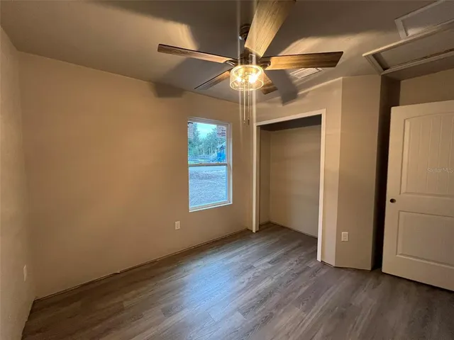 an empty room with wooden floor fan and windows