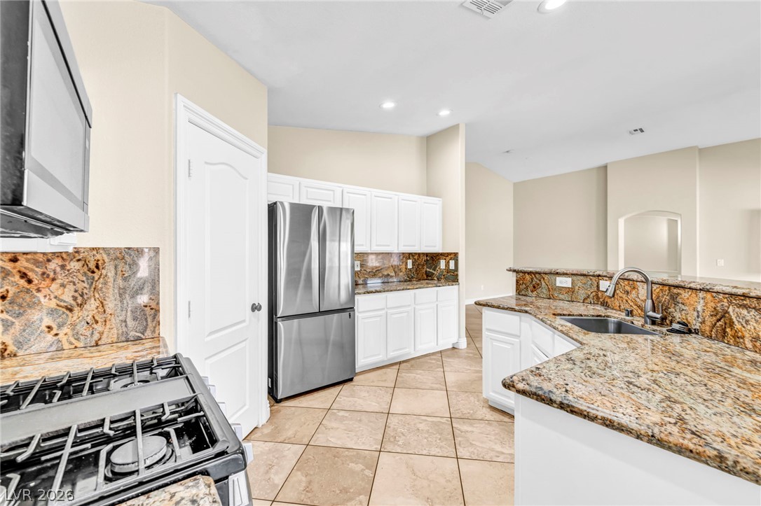 6405 North Raptor Court North Las Vegas, NV 89084 - Photo 23 of 66 An inviting kitchen with pristine white cabinetry, granite countertops, and modern appliances perfect for culinary adventures.
