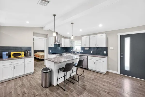 a kitchen with a sink a stove a refrigerator and white cabinets with wooden floor