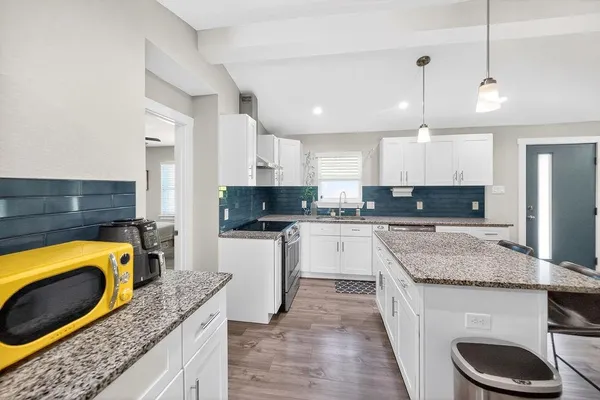 a kitchen with granite countertop kitchen island stainless steel appliances a sink a stove a microwave a center island and cabinets