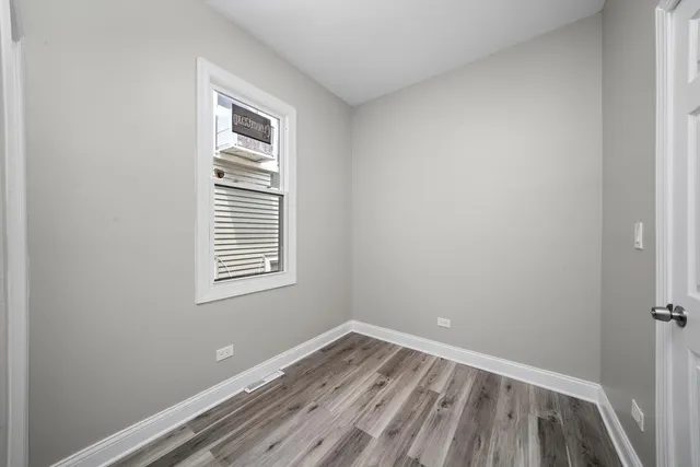 a view of a room that has wooden floor and window in it