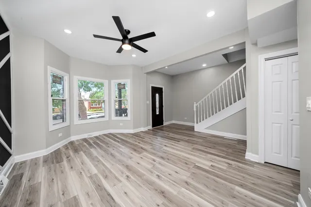 a view of empty room with wooden floor and fan