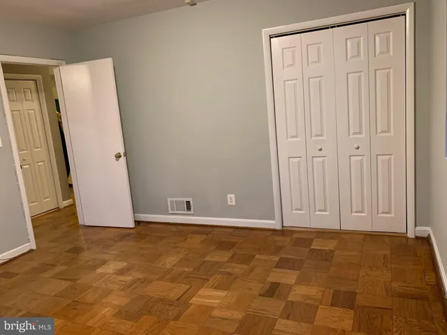 an empty room with wooden floor and mirror