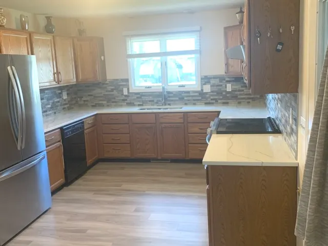 a kitchen with kitchen island granite countertop a sink a counter top space and stainless steel appliances