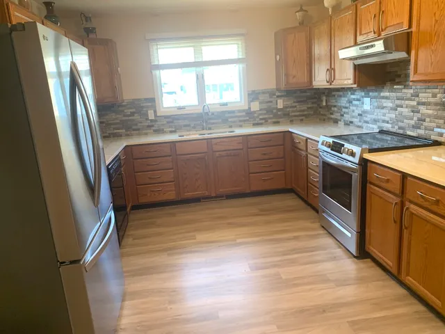 a kitchen with stainless steel appliances granite countertop a sink a stove a refrigerator and cabinets