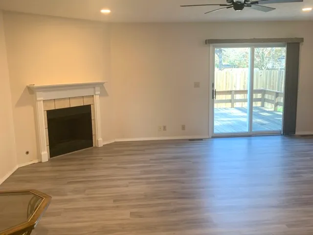 an empty room with wooden floor fireplace and windows