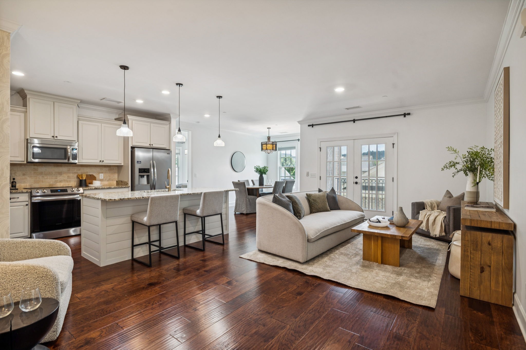 a living room with furniture kitchen and a wooden floor