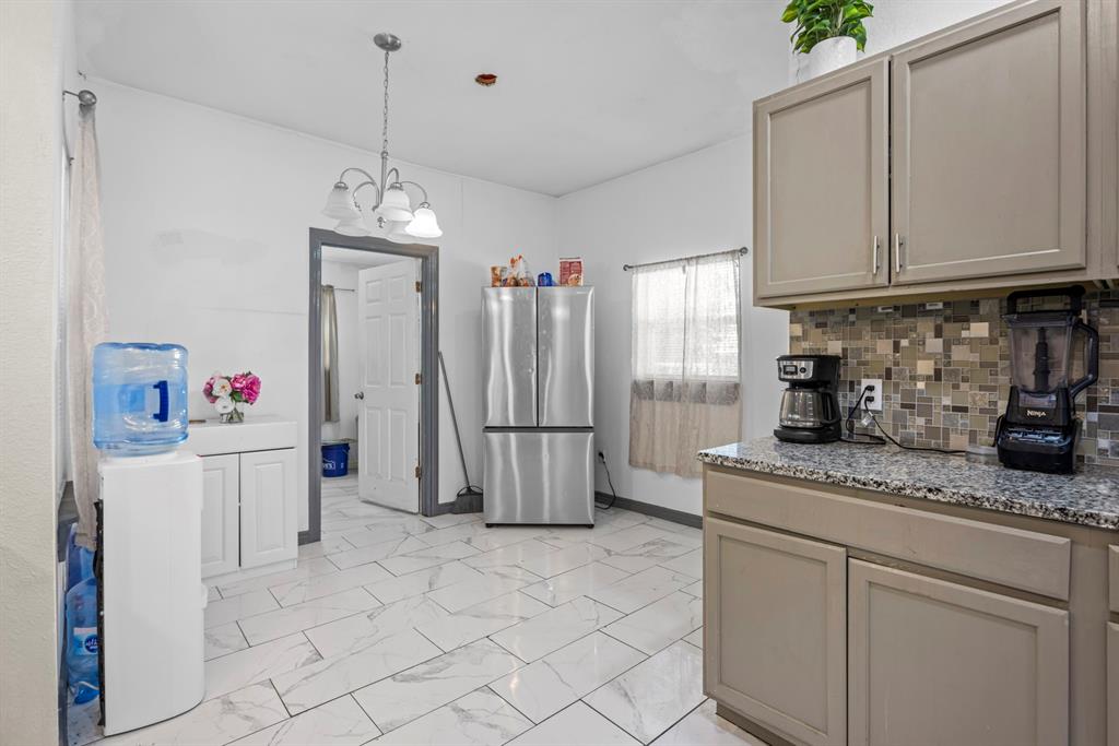 811 Ward Street Marlin, TX 76661 - Photo 9 of 31 Kitchen featuring freestanding refrigerator, gray cabinetry, a chandelier, light marble finish flooring, and decorative backsplash