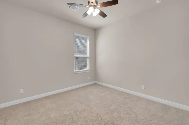 en empty room with windows and chandelier fan