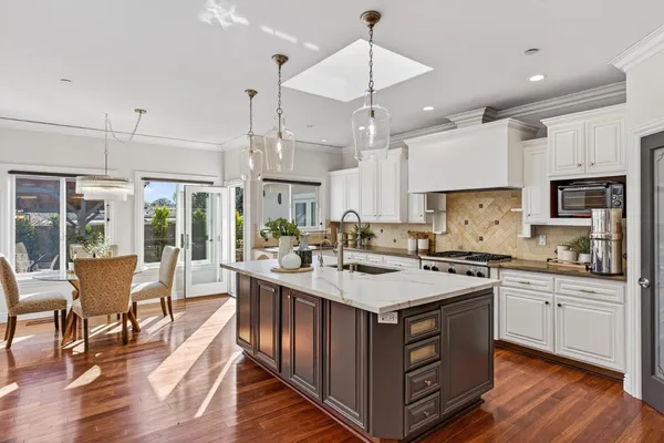 a kitchen with stainless steel appliances a sink a stove a refrigerator cabinets and chairs