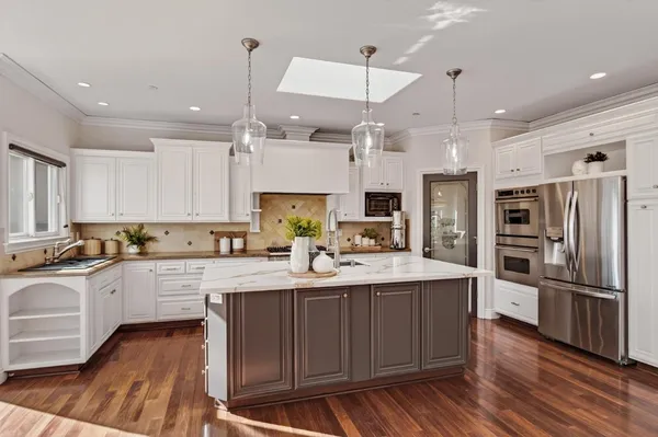 a kitchen with stainless steel appliances kitchen island granite countertop a sink stove and refrigerator