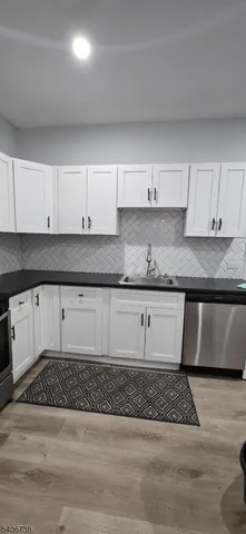 a kitchen with granite countertop a stove a sink and a white cabinets