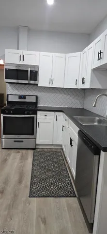 a kitchen with granite countertop a stove sink and cabinets