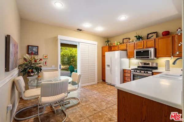 a kitchen with stainless steel appliances a dining table chairs refrigerator and sink