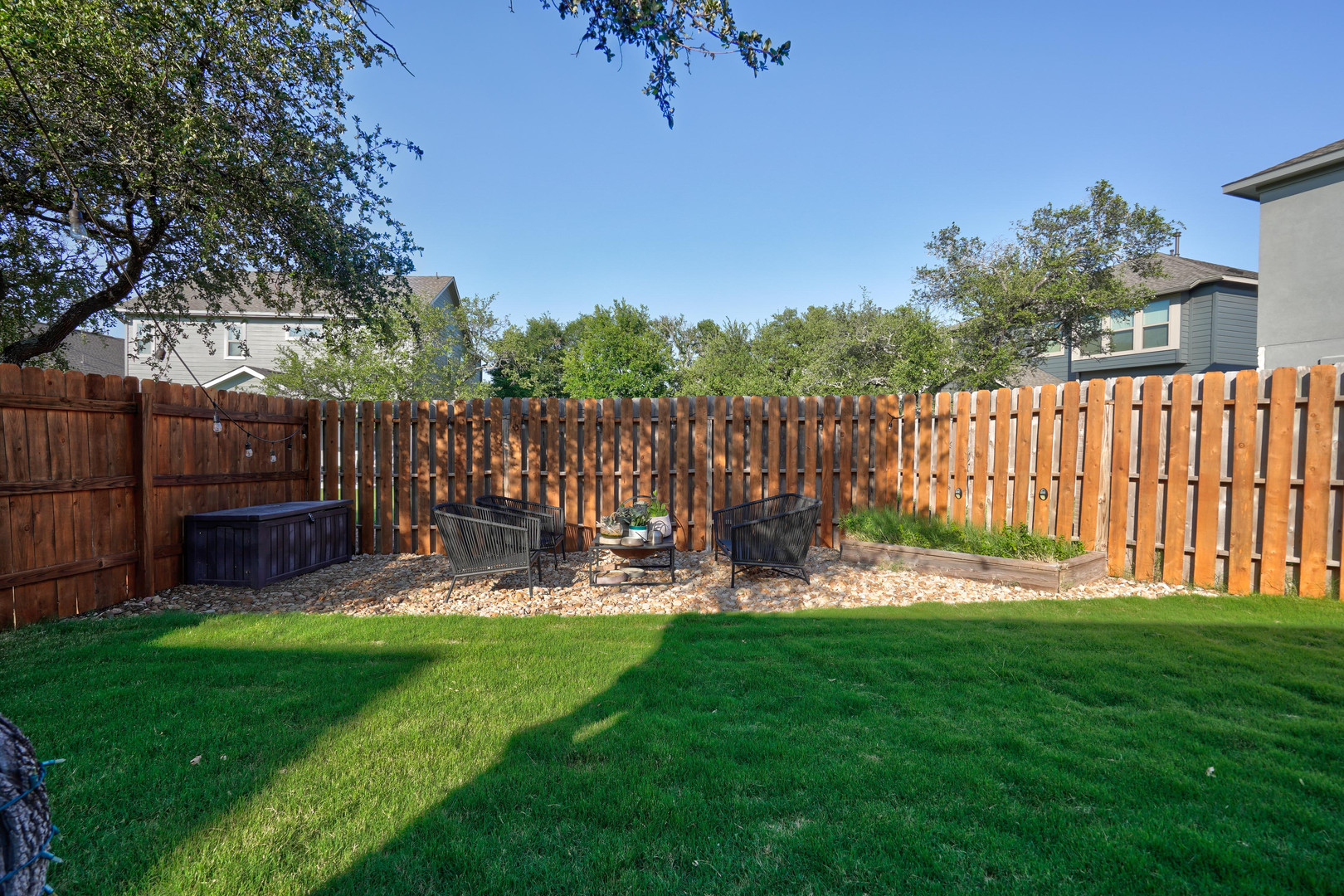 2240 Ringstaff Road Leander, TX 78641 - Photo 23 of 25 Private backyard featuring manicured lawn, full wood privacy fencing, a gravel seating area, a raised planter bed, and mature perimeter trees