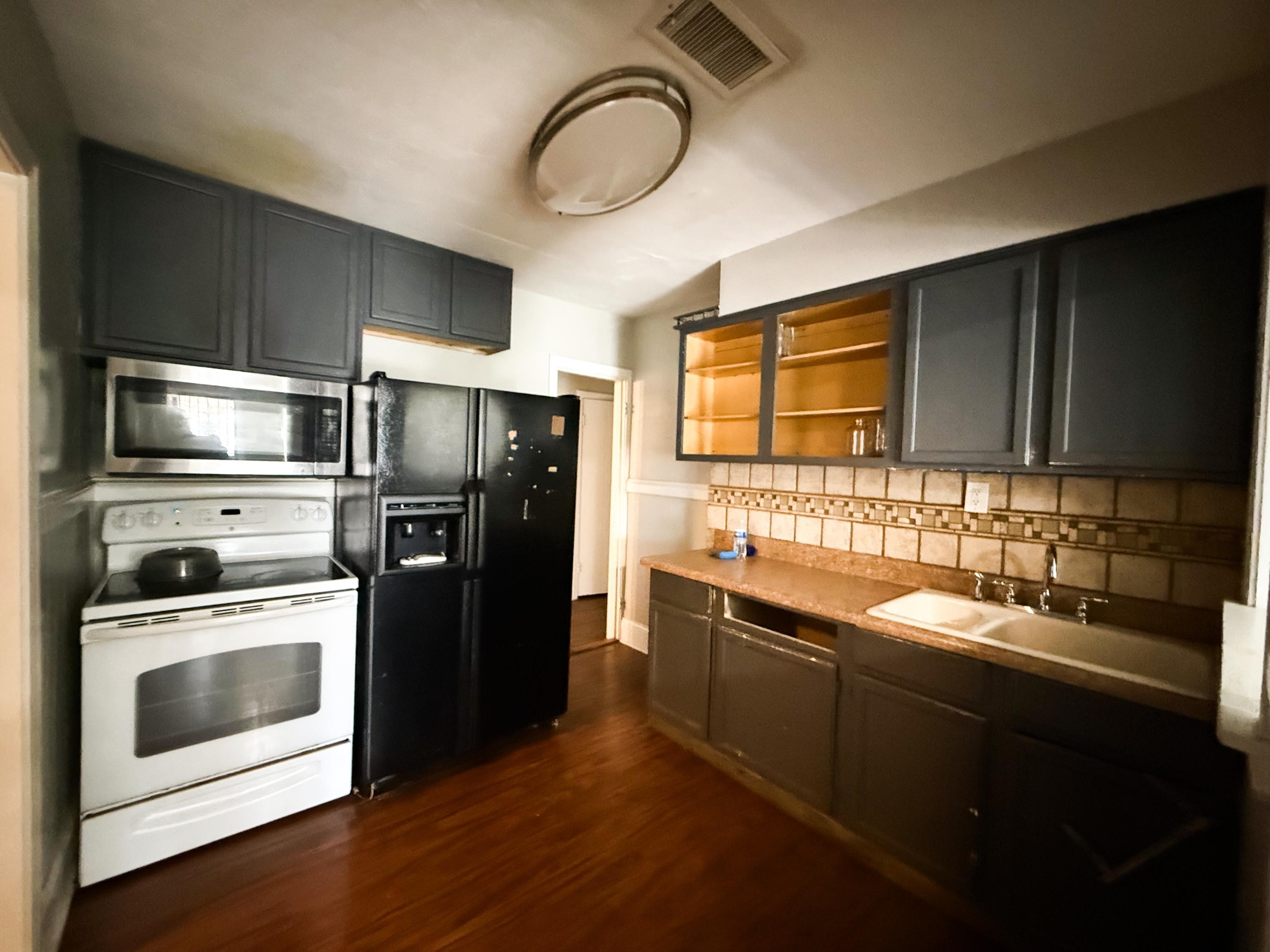 1027 Waring Road Memphis, TN 38122 - Photo 4 of 14 Kitchen featuring white range with electric stovetop, stainless steel microwave, black refrigerator with ice dispenser, light countertops, and open shelves