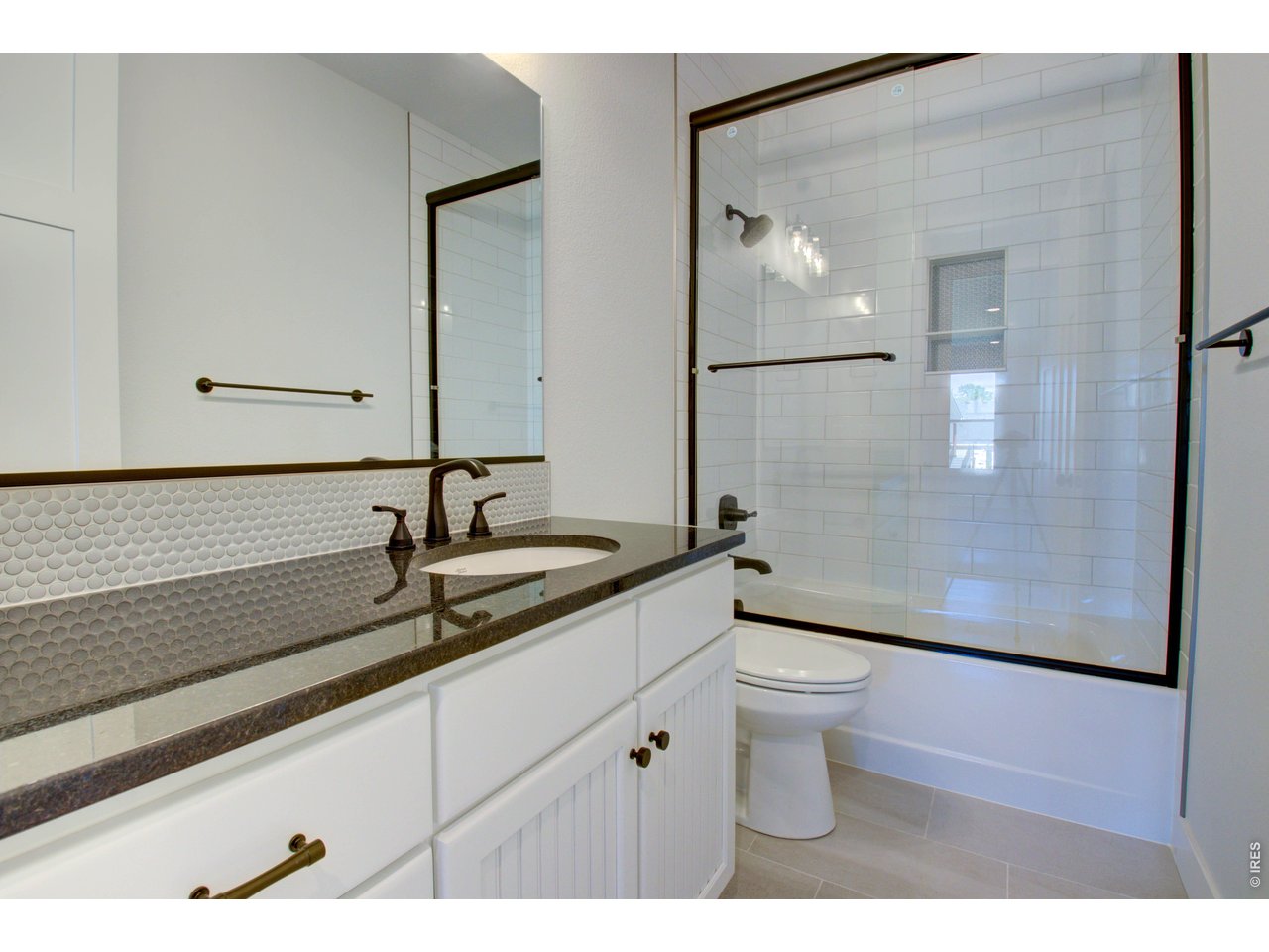 5705 2nd Road Greeley, CO 80634 - Photo 32 of 46 This is the full main/guest bath with a large granite countertop, full wall mirror, soft close cabinetry, glass shower door and a full wall tile tub/shower surround.