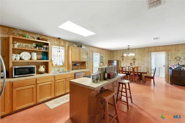 a living room with furniture a kitchen view and a refrigerator