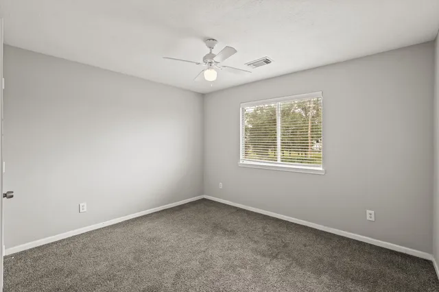 an empty room with a window and a fan