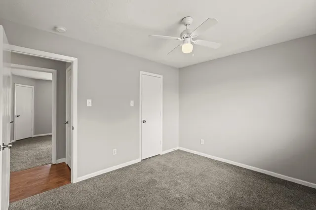an empty room with a chandelier fan and a bathroom
