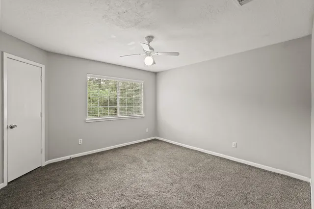 an empty room with windows and ceiling fan