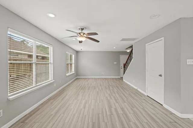 a view of an empty room with a window and wooden floor