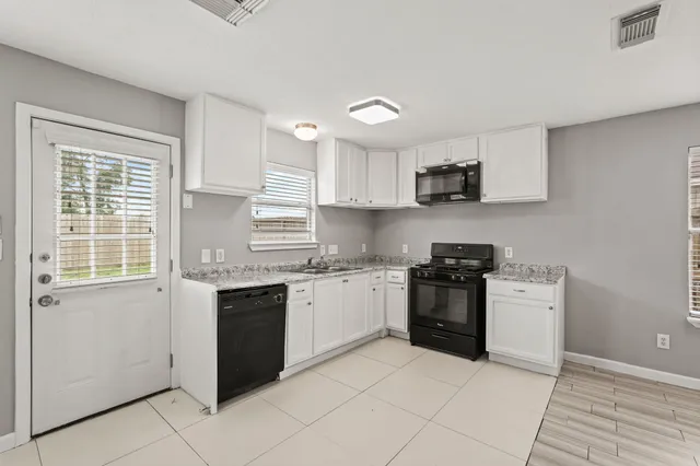 a kitchen with stainless steel appliances granite countertop a stove top oven a sink dishwasher and a refrigerator