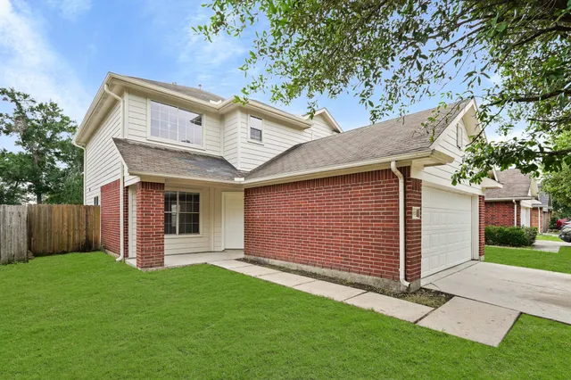 a view of a house with a yard plants and large tree
