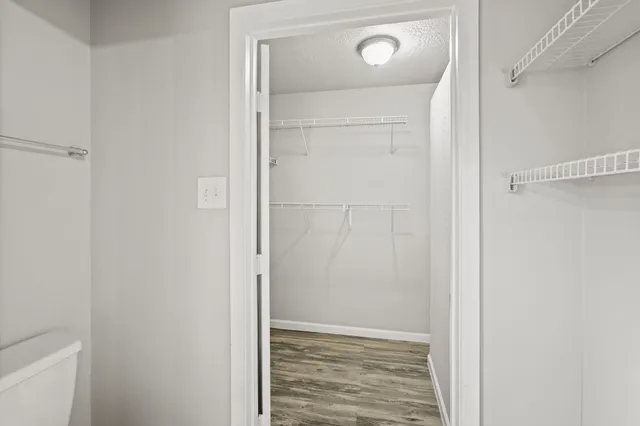 a view of an empty room with closet and wooden floor