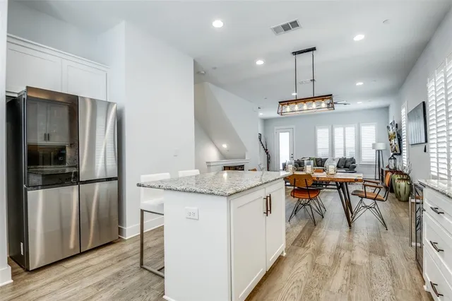 a kitchen with stainless steel appliances kitchen island granite countertop a table chairs in it and wooden floors