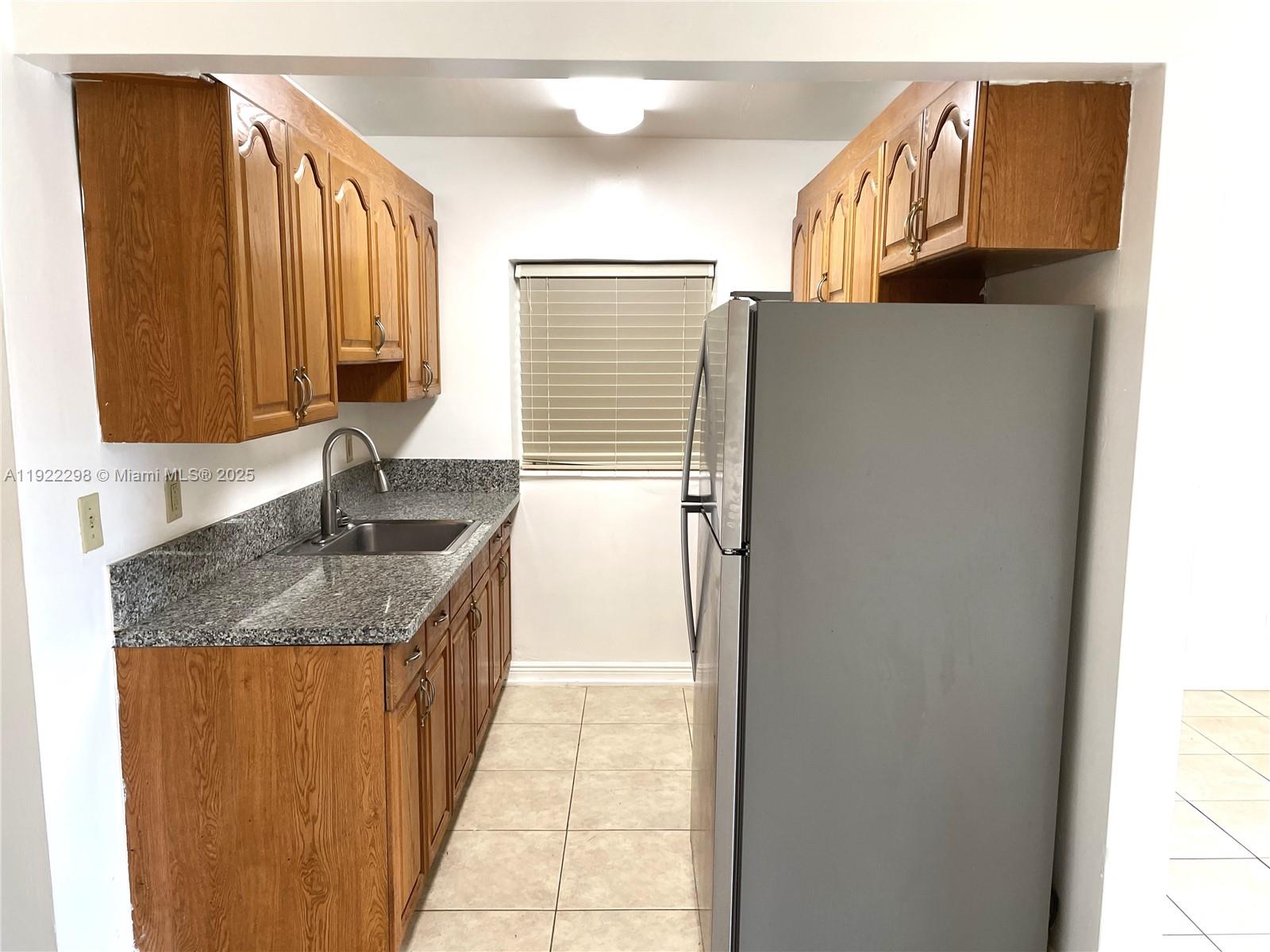 2121 Northeast 40th Court, Unit 2 Lighthouse Point, FL 33064 - Photo 6 of 11 a kitchen with a granite countertop sink and a refrigerator