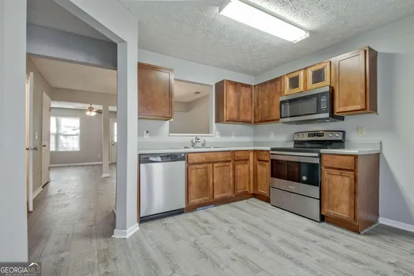 a kitchen with stainless steel appliances granite countertop a stove top oven a sink and dishwasher a refrigerator with wooden floor