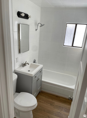 230 North 2nd Street Tooele, UT 84074 - Photo 8 of 18 Bathroom featuring wood-finish flooring, a white tiled shower surround, a compact vanity with basin sink, a wall-mounted medicine cabinet, and an integrated bathtub